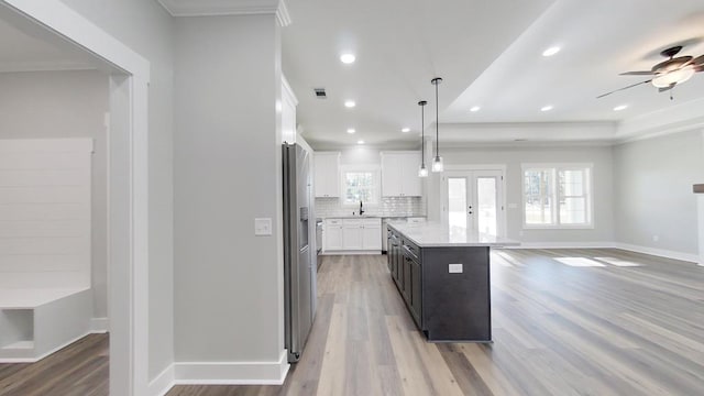 kitchen featuring a kitchen island, decorative light fixtures, tasteful backsplash, white cabinets, and crown molding