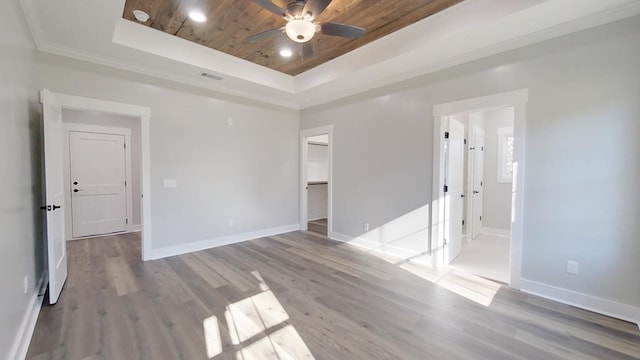 empty room featuring wood-type flooring, wooden ceiling, a raised ceiling, and ceiling fan