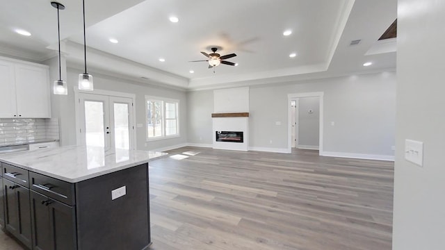 kitchen with a raised ceiling, a center island, pendant lighting, and white cabinets