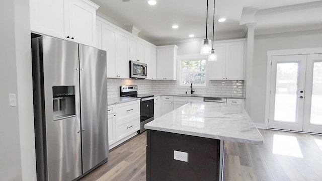 kitchen with appliances with stainless steel finishes, decorative light fixtures, a kitchen island, and white cabinets