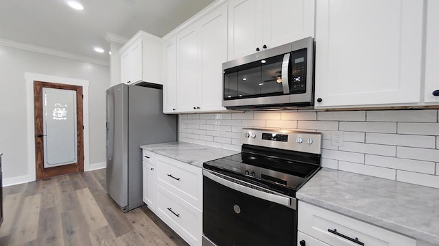 kitchen featuring stainless steel appliances, crown molding, white cabinets, and light stone counters