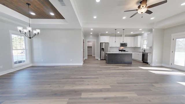 kitchen with pendant lighting, white cabinetry, stainless steel appliances, and a tray ceiling