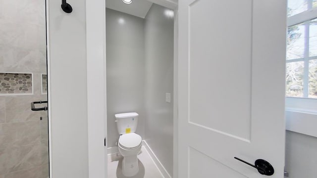 bathroom with a tile shower and toilet