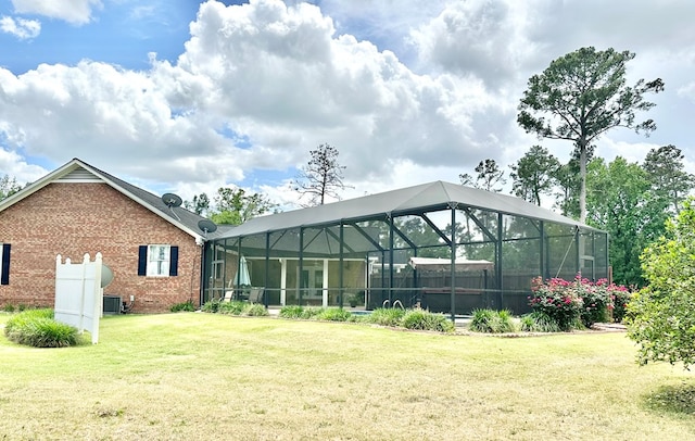 back of property featuring cooling unit, a lanai, and a lawn