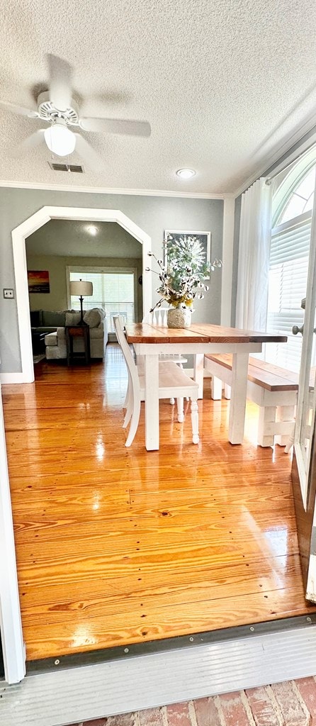 unfurnished dining area with ceiling fan, a textured ceiling, and hardwood / wood-style flooring