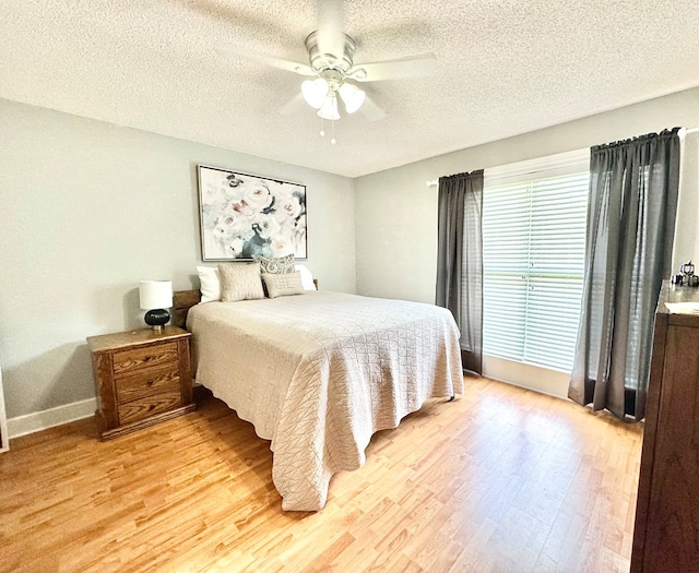 bedroom with a textured ceiling, light hardwood / wood-style flooring, and ceiling fan