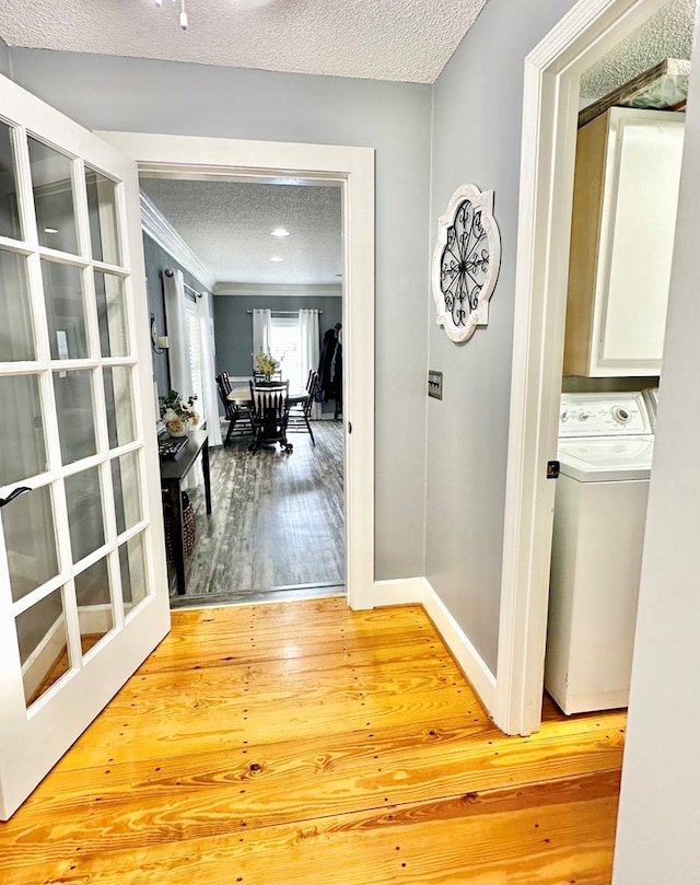 corridor with hardwood / wood-style flooring, ornamental molding, a textured ceiling, and washer / dryer