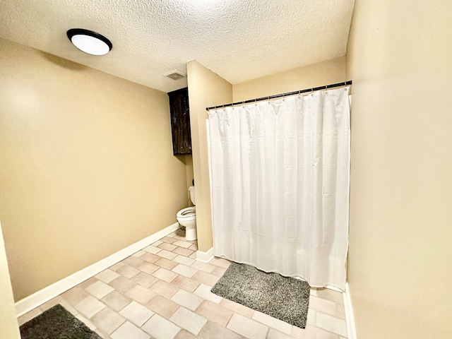 bathroom with a textured ceiling and toilet