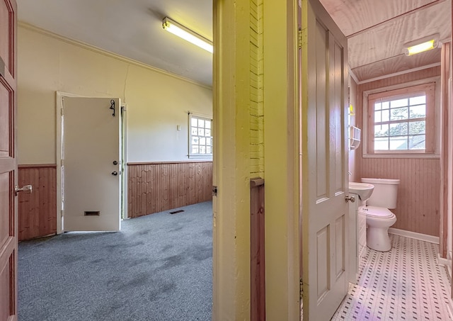 bathroom with wooden walls, toilet, and ornamental molding