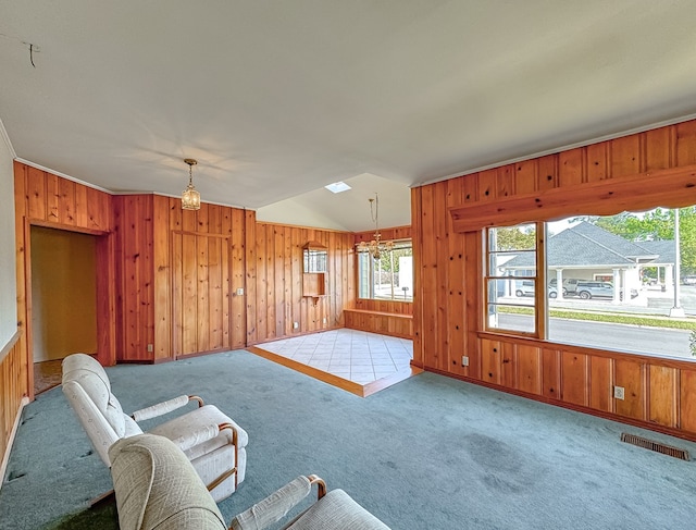 living area with a chandelier, wood walls, light carpet, and ornamental molding