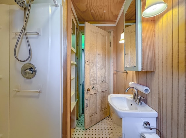 bathroom with sink, walk in shower, and wood walls