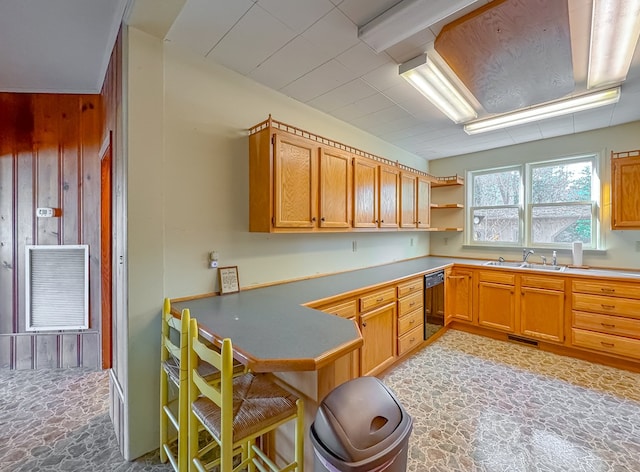 kitchen featuring kitchen peninsula, wood walls, and sink