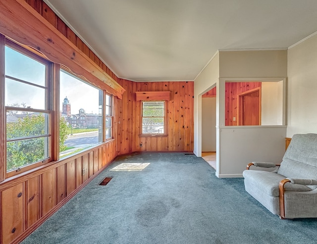 unfurnished room featuring wood walls, carpet floors, and crown molding