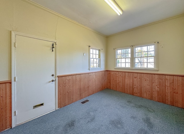 carpeted empty room featuring wood walls and ornamental molding