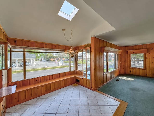 unfurnished sunroom featuring vaulted ceiling with skylight and an inviting chandelier