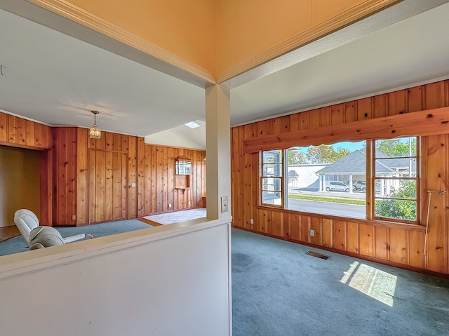 unfurnished living room with carpet, wood walls, and an inviting chandelier