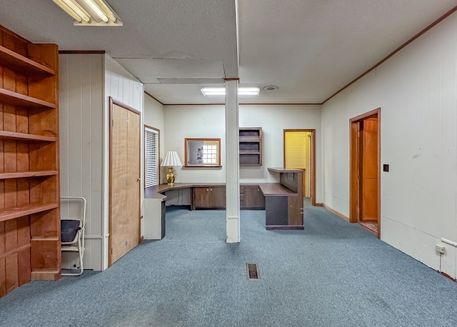 interior space with carpet flooring, wood walls, crown molding, and a textured ceiling