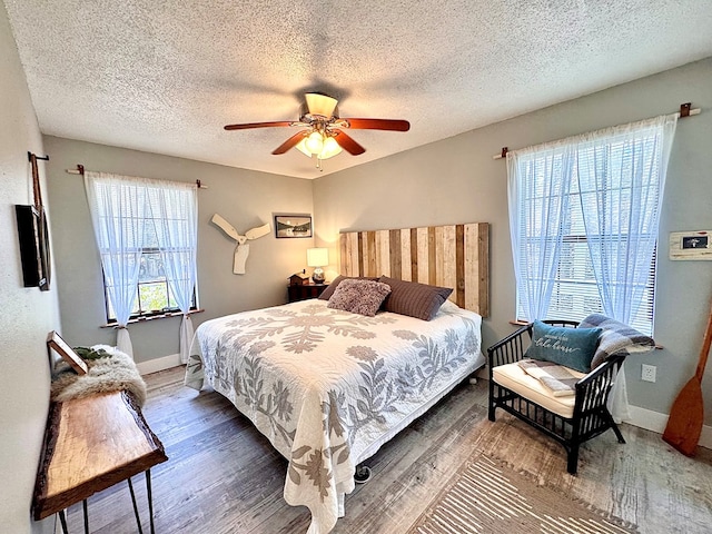 bedroom with a textured ceiling, dark hardwood / wood-style floors, and ceiling fan