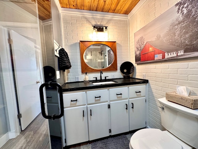 bathroom featuring vanity, brick wall, wood ceiling, and toilet