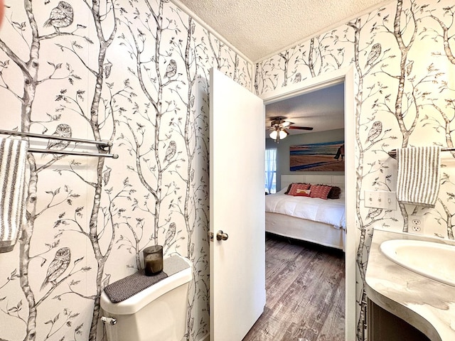 bathroom with toilet, a textured ceiling, vanity, ceiling fan, and hardwood / wood-style floors