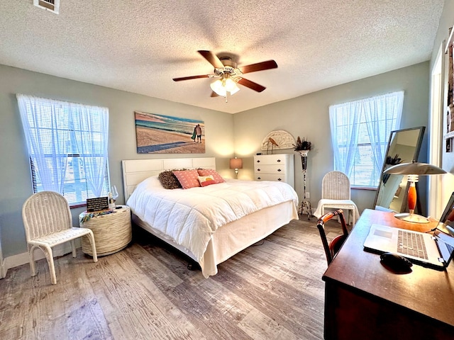 bedroom with ceiling fan, hardwood / wood-style floors, and a textured ceiling