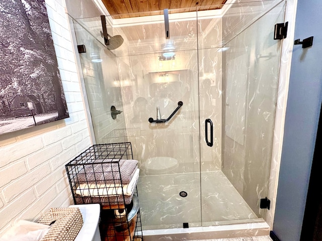 bathroom with brick wall and a shower with shower door