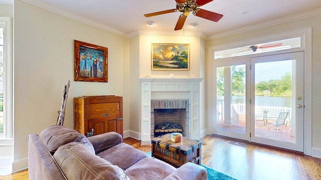 1389 Lake Front Dr, Cairo, GA 39828 - living room with ceiling fan, crown molding, light wood finished floors, a water view, and a fireplace