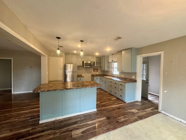 kitchen featuring pendant lighting, sink, stainless steel appliances, and a center island