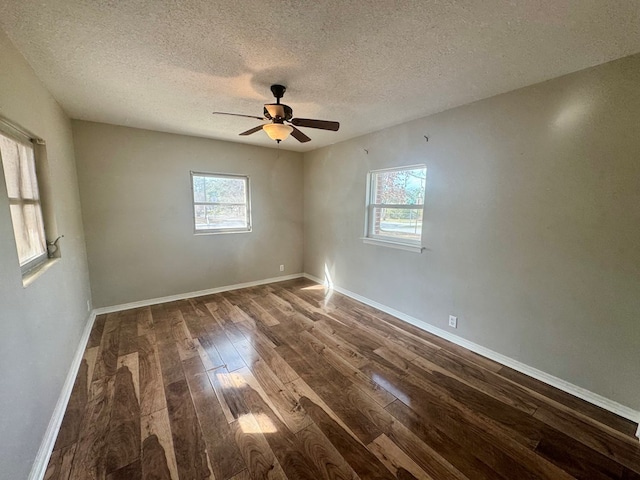 empty room featuring ceiling fan, plenty of natural light, dark hardwood / wood-style floors, and a textured ceiling