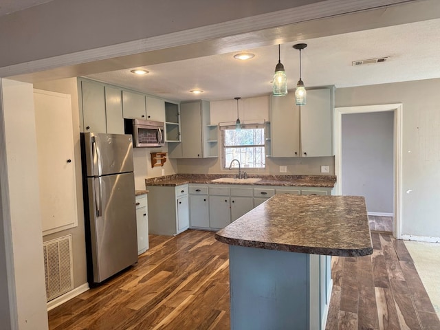 kitchen with sink, dark wood-type flooring, hanging light fixtures, stainless steel appliances, and a center island