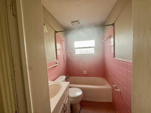 full bathroom featuring tile walls, a textured ceiling, tile patterned floors, toilet, and tiled shower / bath