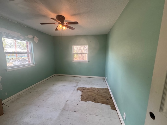 spare room with ceiling fan, a wealth of natural light, and a textured ceiling