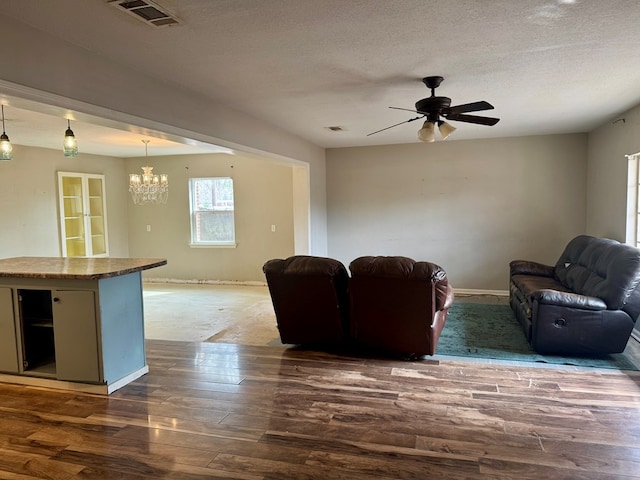 unfurnished living room featuring dark hardwood / wood-style flooring, ceiling fan with notable chandelier, and a textured ceiling