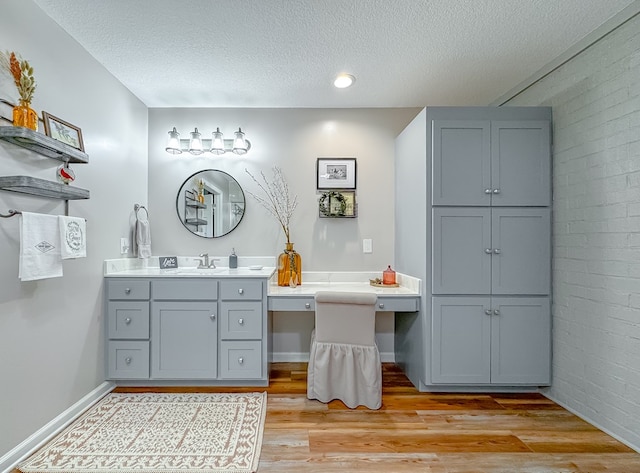 1415 College Rd, Bainbridge, GA 39819 - bathroom with a textured ceiling, wood finished floors, vanity, brick wall, and baseboards