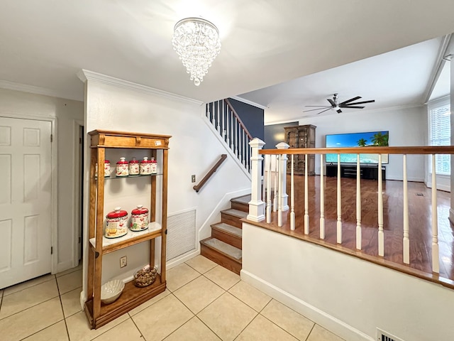 staircase with ceiling fan with notable chandelier, tile patterned floors, and ornamental molding