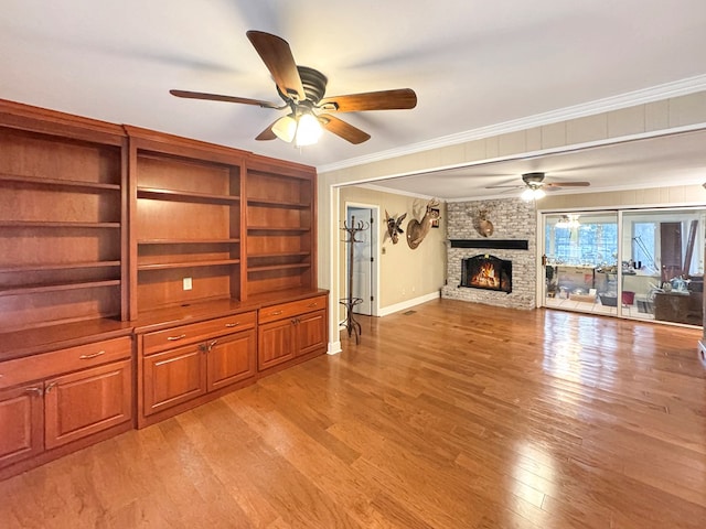 unfurnished living room with light hardwood / wood-style floors, a brick fireplace, and crown molding