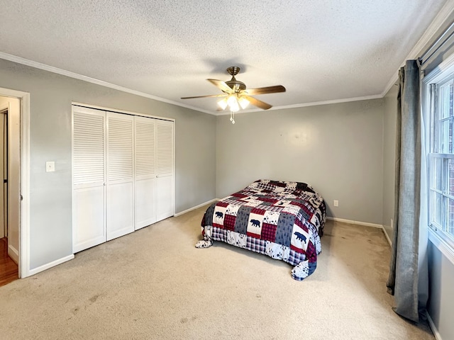 carpeted bedroom with a closet, a textured ceiling, ceiling fan, and crown molding