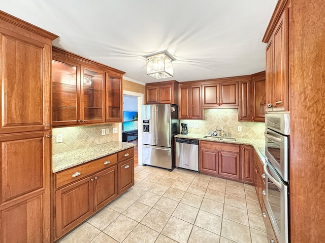 kitchen with appliances with stainless steel finishes, backsplash, light tile patterned flooring, and light stone countertops