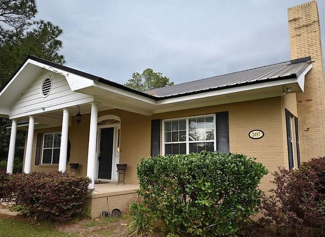 2497 Vada Rd, Bainbridge, GA 39817 - view of exterior entry with covered porch, a chimney, and metal roof