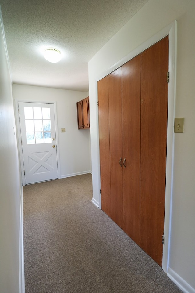 hall featuring a textured ceiling and light colored carpet