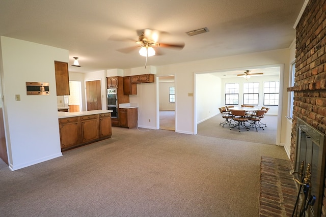 kitchen with light carpet, a fireplace, ceiling fan, and stainless steel double oven