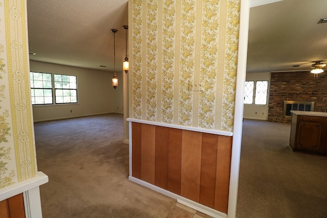 interior space with a textured ceiling, dark carpet, a healthy amount of sunlight, and wood walls