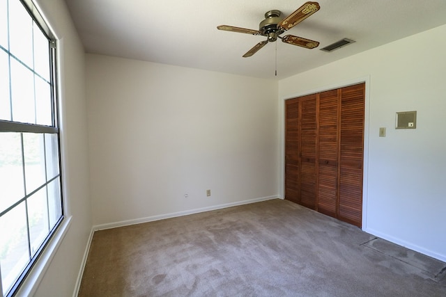 unfurnished bedroom with carpet flooring, a closet, multiple windows, and ceiling fan