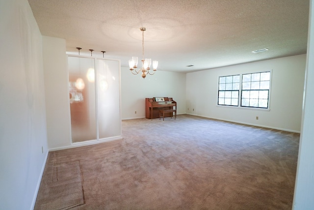 spare room with carpet, a chandelier, and a textured ceiling