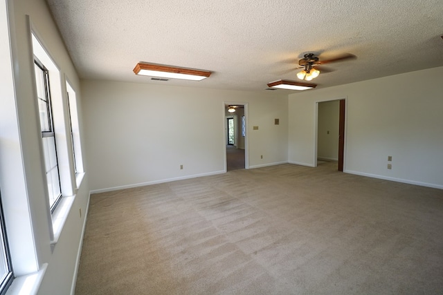 carpeted empty room with ceiling fan and a textured ceiling