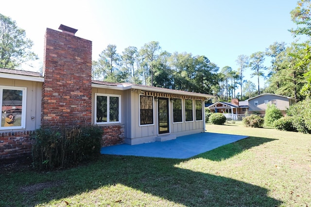 rear view of property featuring a lawn and a patio area