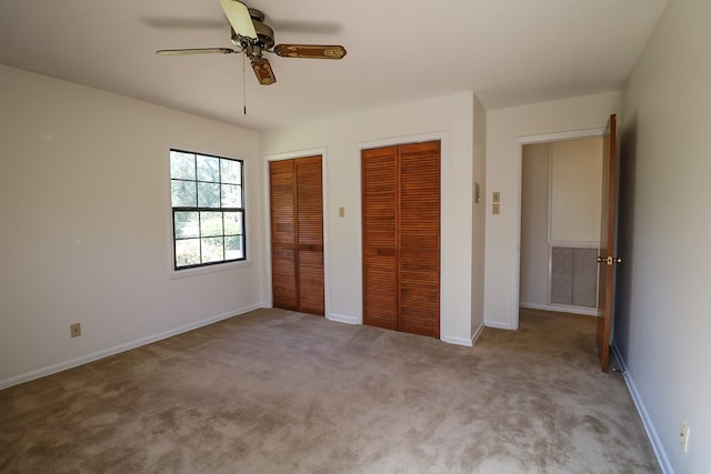 unfurnished bedroom featuring light carpet, two closets, and ceiling fan