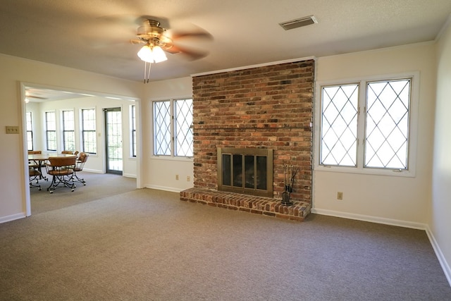 unfurnished living room featuring carpet flooring, ceiling fan, a textured ceiling, and a brick fireplace