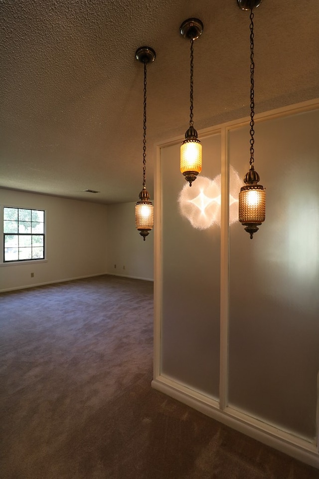 interior space featuring dark carpet and a textured ceiling