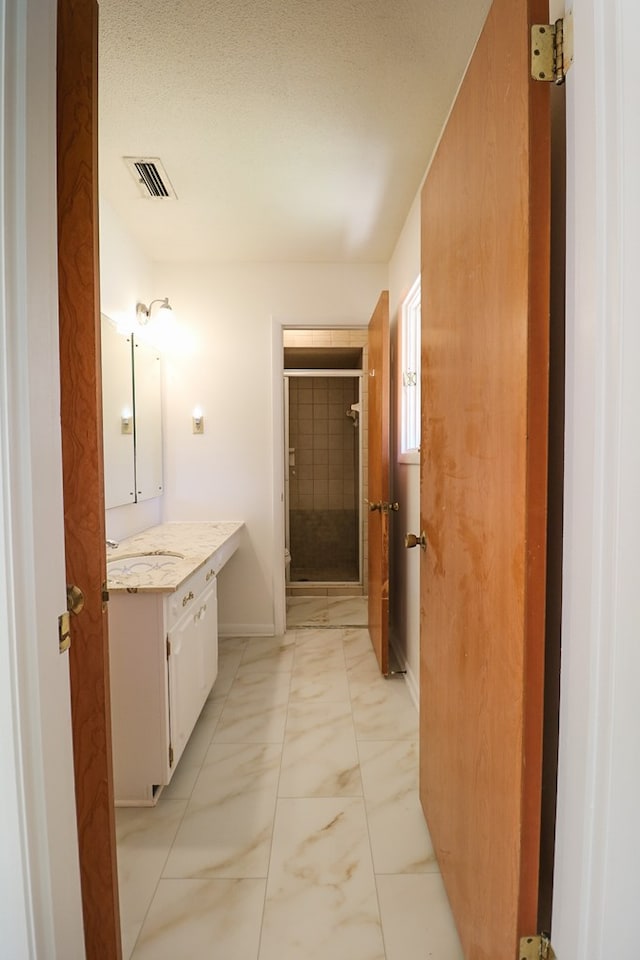 bathroom featuring a tile shower, vanity, and a textured ceiling